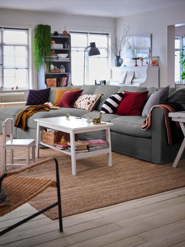 A large living room with a grey GRÖNLID four-seat sofa with chaise longues, a white LUNNARP coffee table standing next to it.