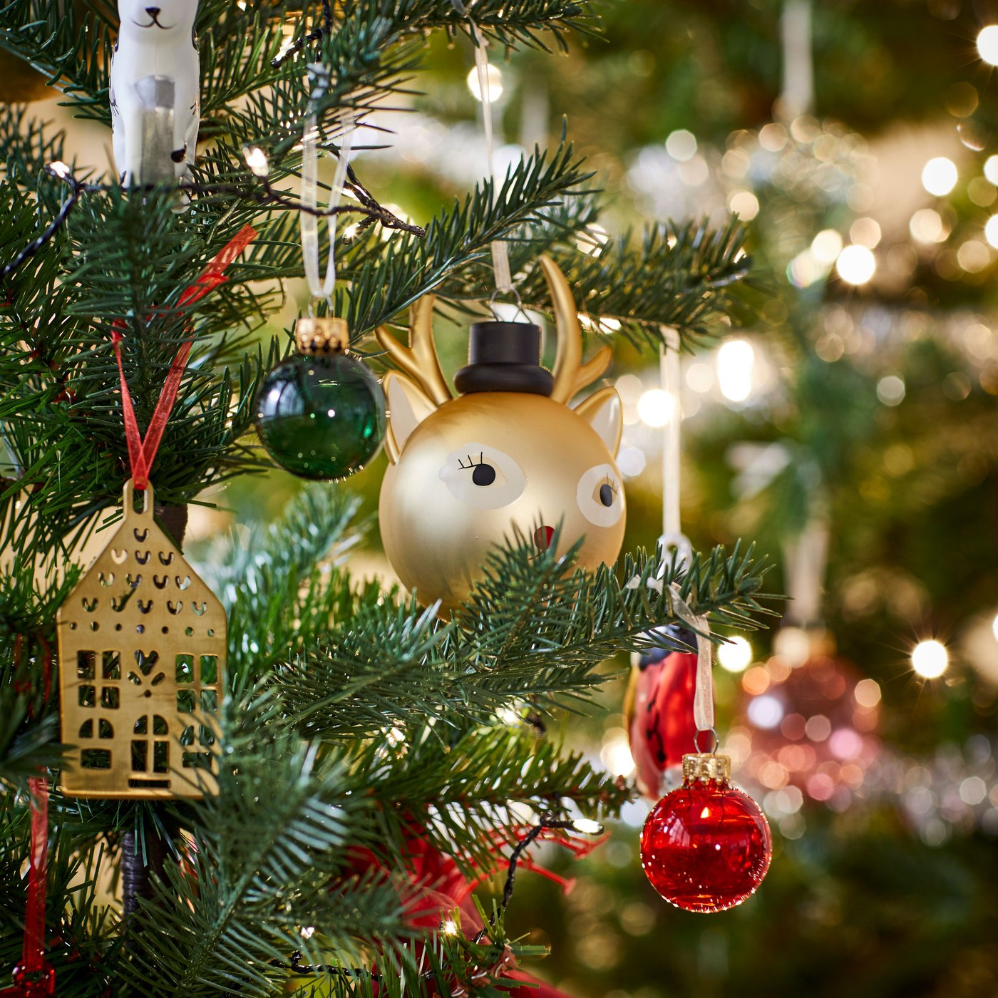 Bild på julgranspynt i olika stilar som hänger i en julgran.