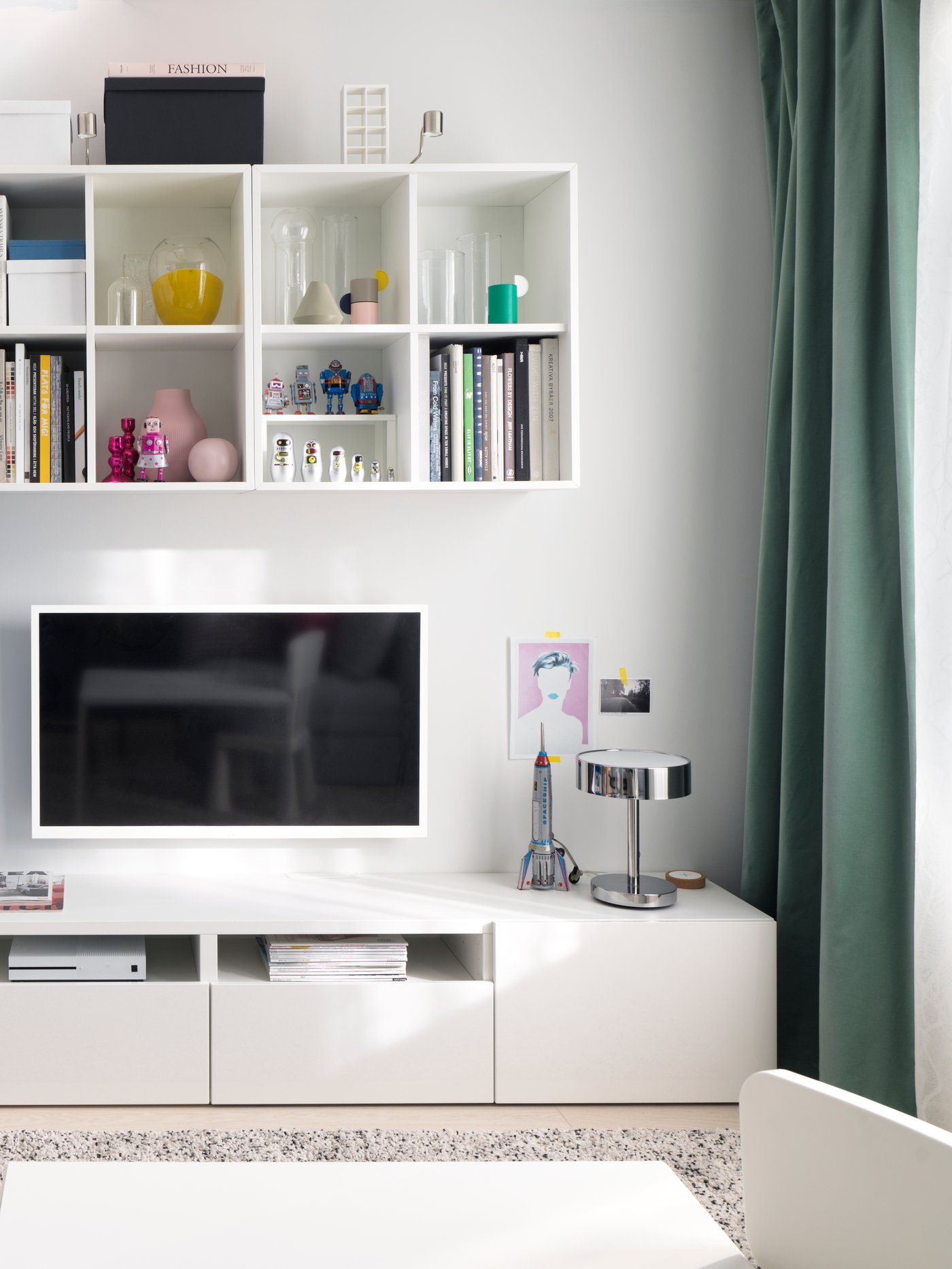 En stue med en tv-væg med en tv-bænk og et jernsyn der ænger på væggen og oven over hænger en reol med flere rum. 