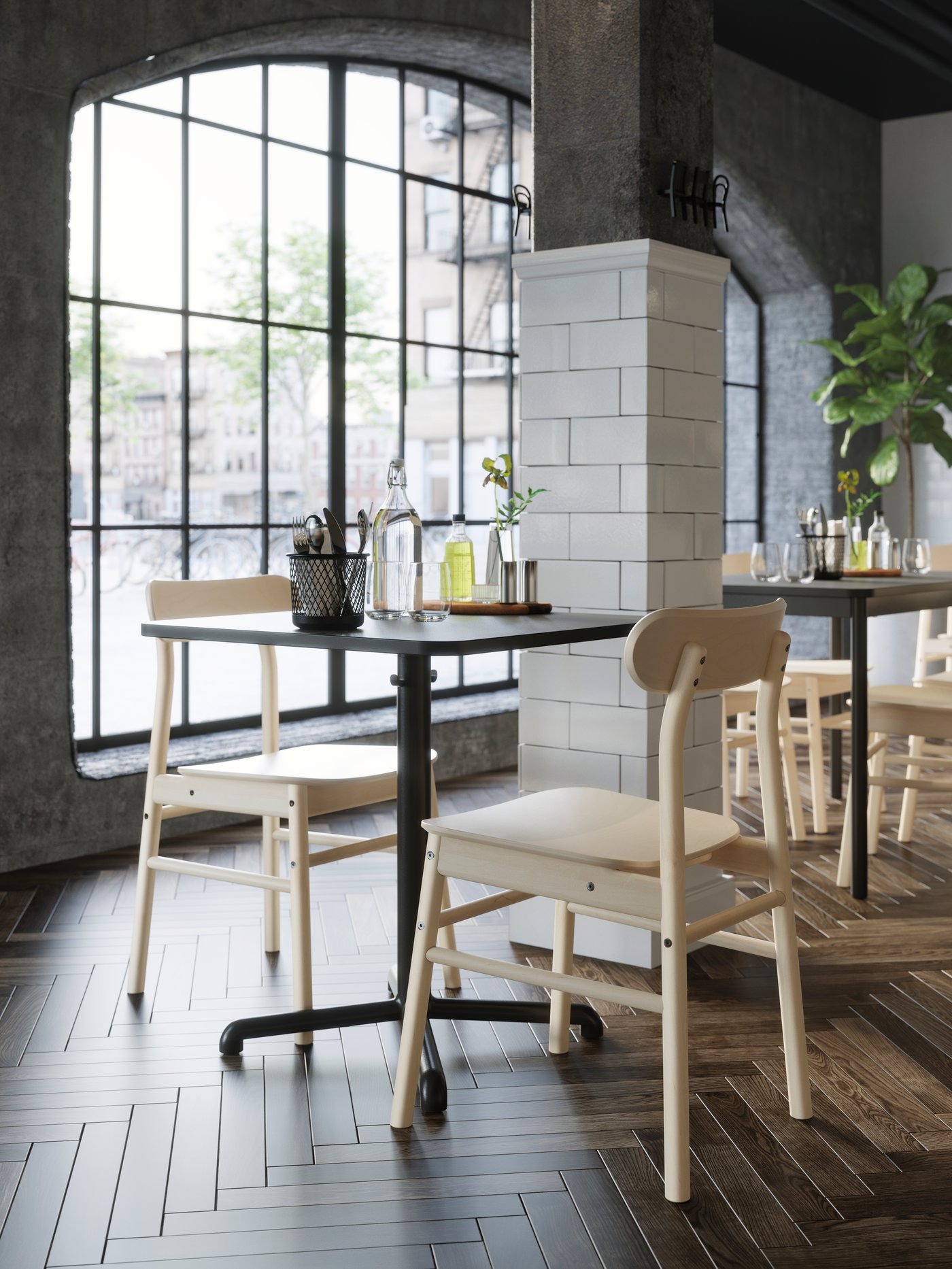 A birch RÖNNINGE chair in a café with black round tables.