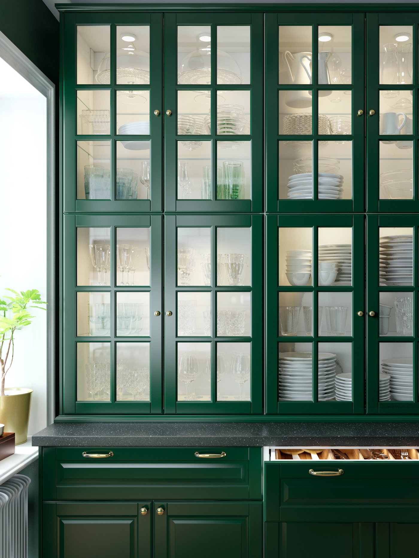Lapan kabinet dinding dengan pintu kaca berwarna hijau gelap dan perincian serong. Kelengkapan hidangan disimpan di dalam kabinet yang bercahaya.