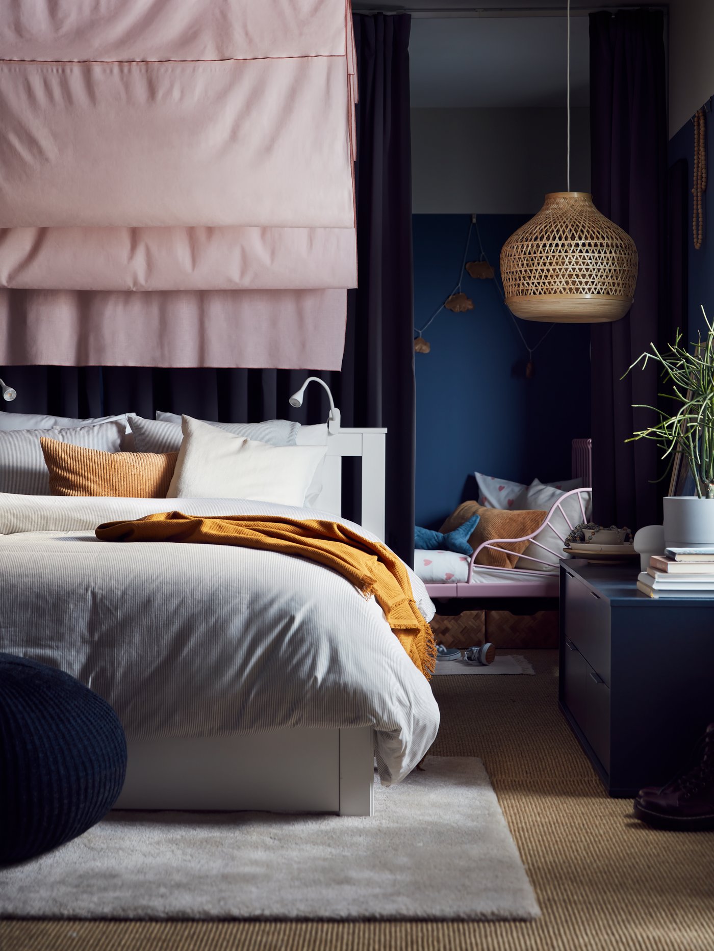 Ropa de cama gris TRINDSTARR sobre base de cama SONGESAND junto a un mueble azul oscuro NORDMELA.