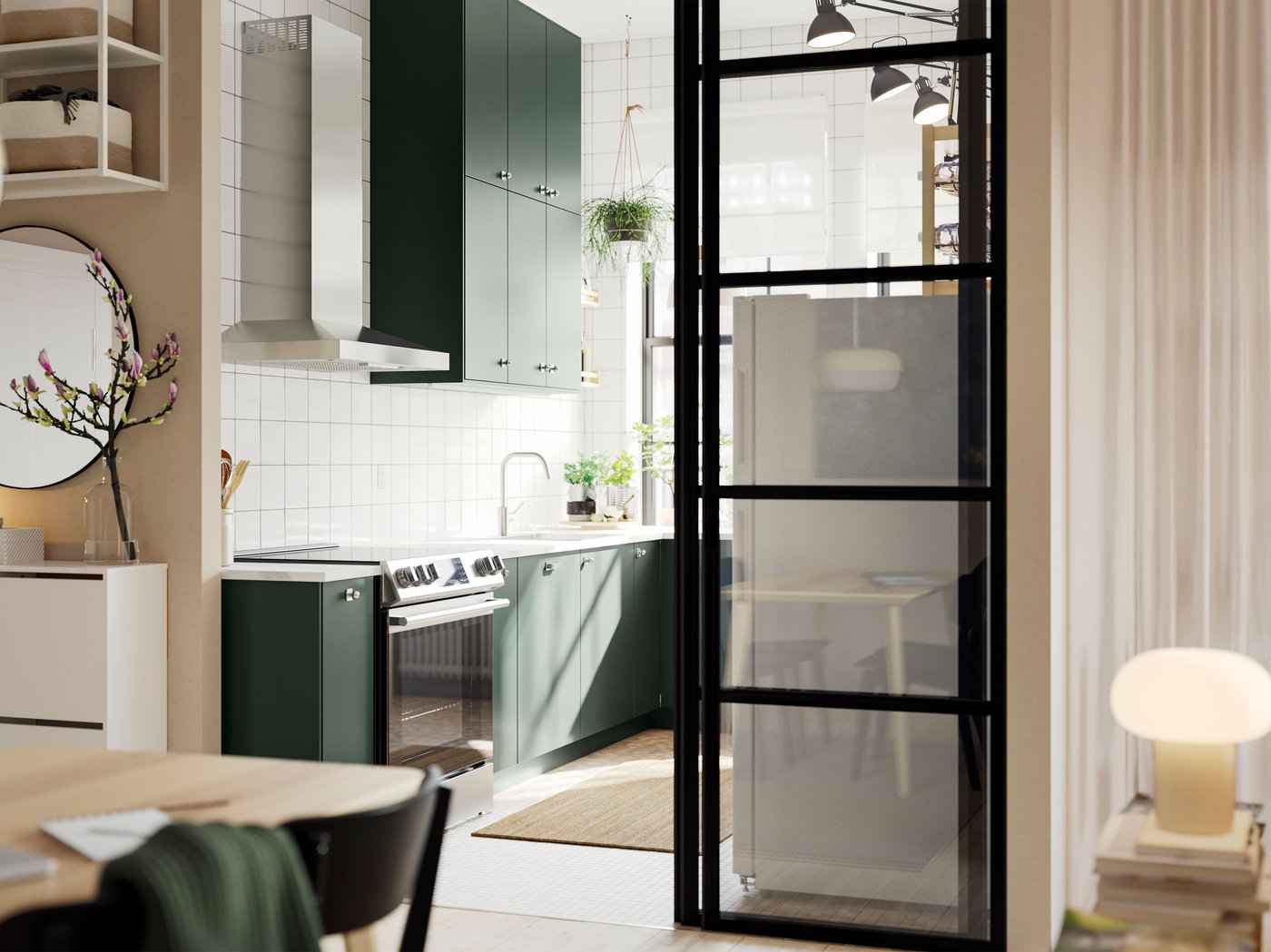 An open kitchen with deep green HAVSTORP kitchen fronts and wall cabinets up to the ceiling, next to a bright living room.