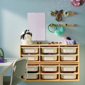 Two light white stained pine TROFAST wall storage frames with white boxes on a wall. There are two FLISAT knob racks above.