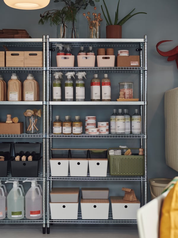 Two OMAR shelves placed against a blue wall, with cleaning supplies and boxes neatly arranged on the shelves.
