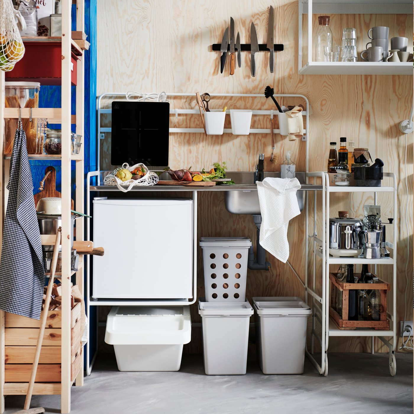 A compact kitchen corner features a white SUNNERSTA mini-kitchen with appliances and storage boxes neatly arranged around it.