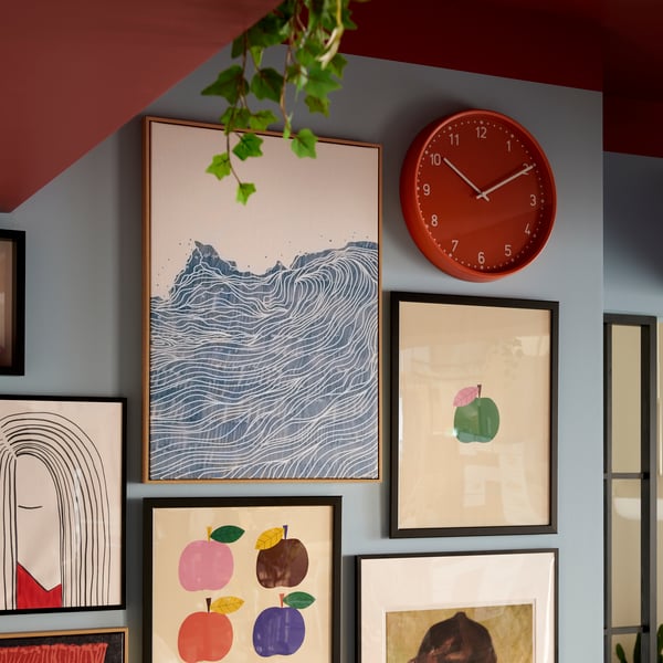 A brightly colored room with a wall section filled with neatly arranged framed art and an orange BONDIS clock.