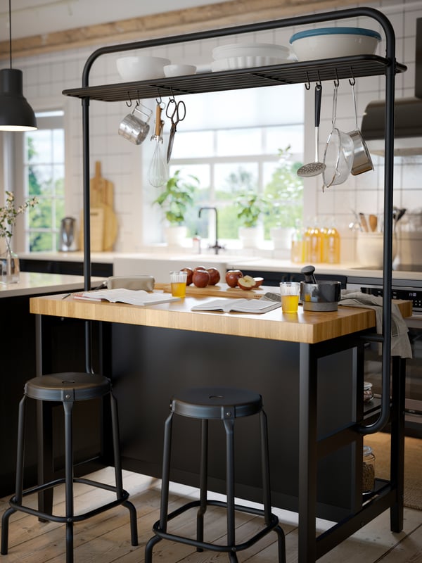 A large kitchen island holding snacks and glasses of wine, with tableware stored on the shelves below.