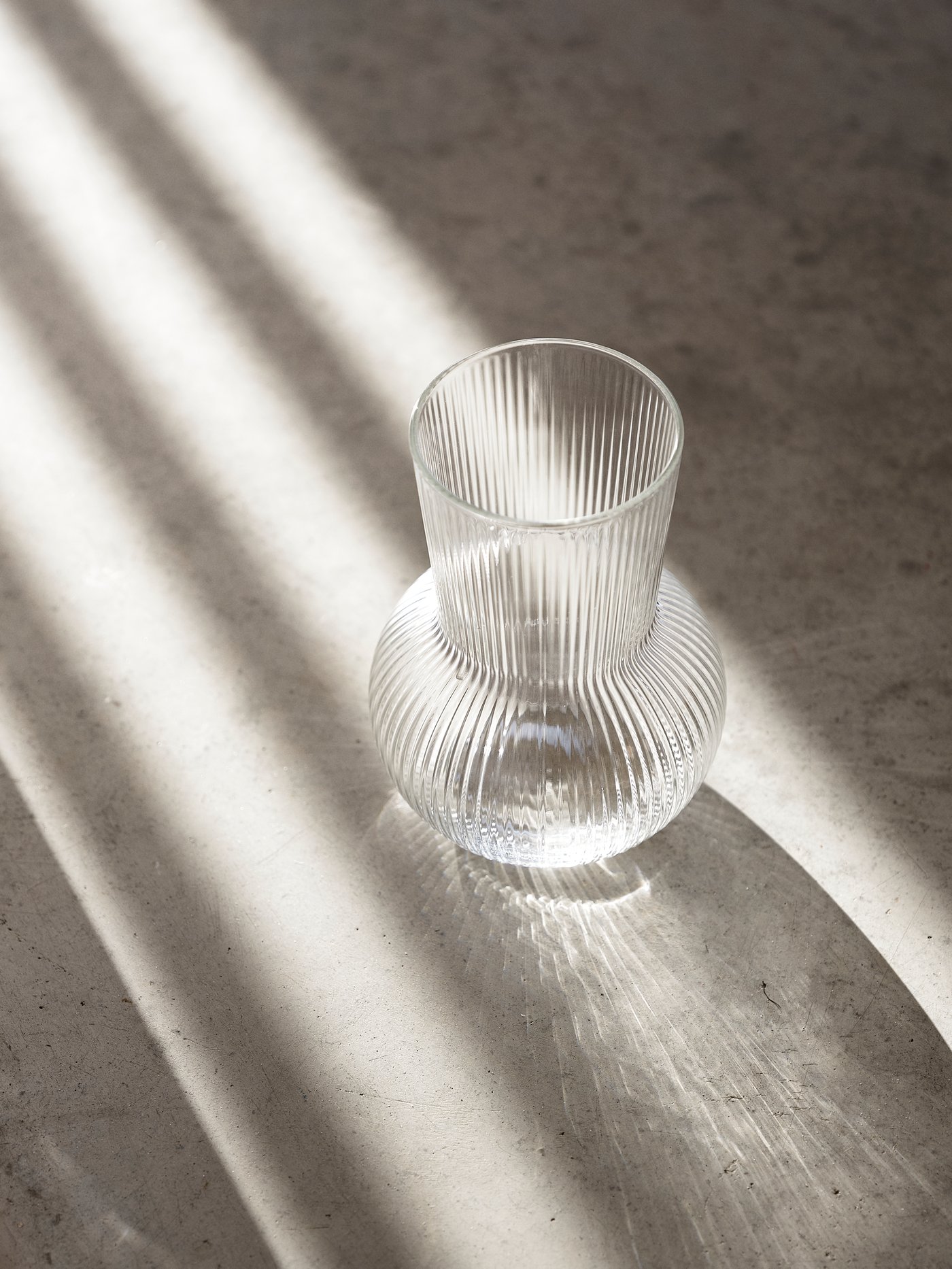 Wazon PÅDRAG na kamiennej podłodze oświetlony mocnym światem z boku.