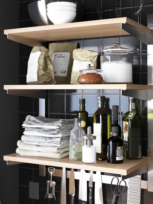 A kitchen with a beige suspension rail with shelf and a magnetic knife rack made of stainless steel and ash supporting items. 