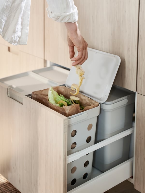 Three white SORTERA bins in a white tiled room where one is stuffed with brown paper.