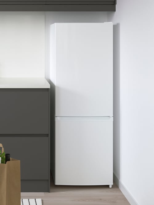 A white LAGAN fridge and freezer combination is next to a base cabinet with dark grey VOXTORP doors and a white countertop.