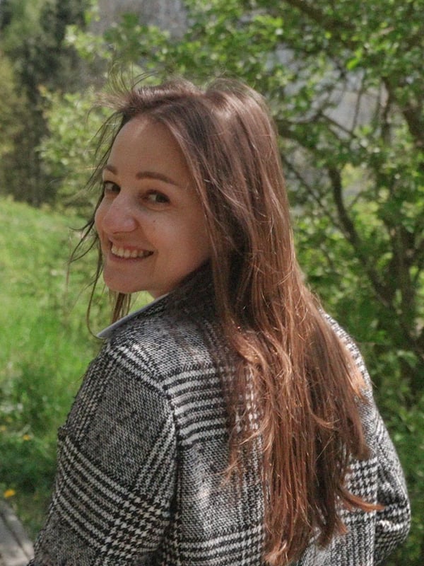 Une femme marchant dans la nature regarde par-dessus son épaule et sourit à l’objectif. 