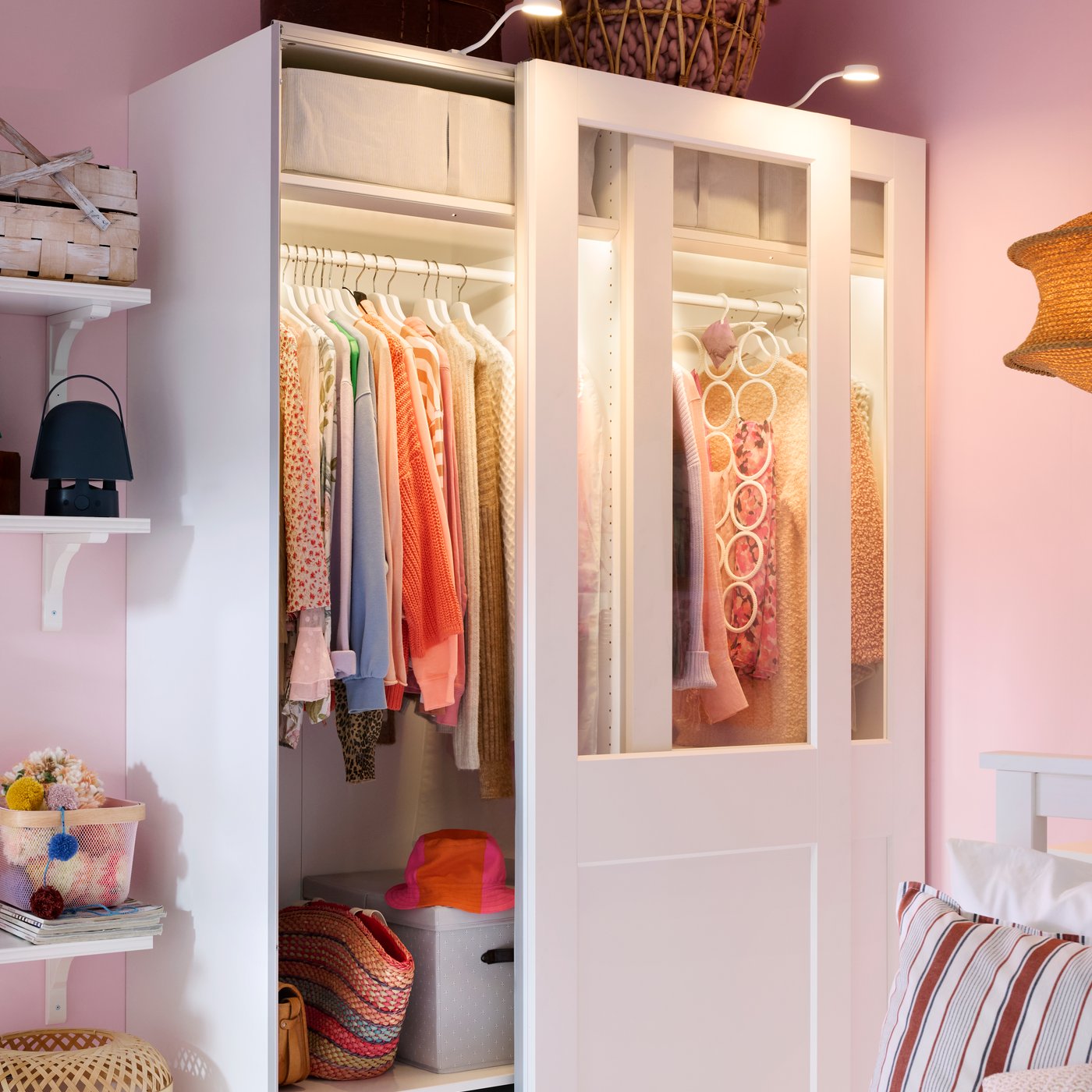 Szafa PAX z białumi drzwiami przesuwnymi i włączonym oświetleniem zintegrowanym.