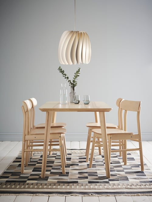 An ash veneer/birch LISABO/RÖNNINGE dining set with a table and four chairs sits on a rug. The table has glasses and a vase.