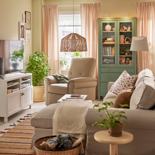 Sala com sofá, poltrona, móvel de TV e vitrina.