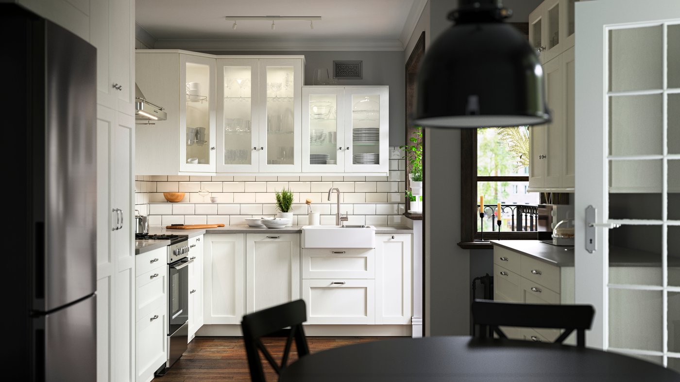 Une cuisine avec des façades ENKÖPING blanches, une cuisinière ÖRMINGE en acier inoxydable, un évier HAVSEN et une suspension SVARTNORA.