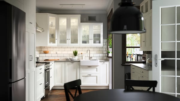 A kitchen with ENKÖPING white fronts, a ÖRMINGE range in stainless steel, a HAVSEN sink bowl and a SVARTNORA pendant lamp.