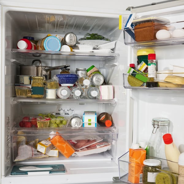 さまざまな食品が詰まった冷蔵庫。飲み物、パック入りの肉、果物、卵、調味料、保存容器に入った料理などが棚やドアポケットにぎっしりと収納されている、一般的な家庭の冷蔵庫の様子。