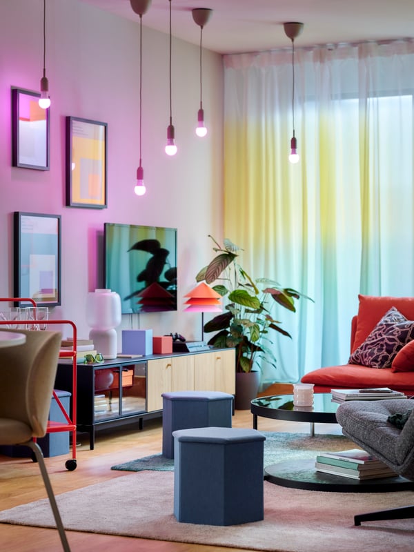 A colorful living room with, among other things, a BOASTAD TV bench and hanging WIRELESS lamps from the ceiling.