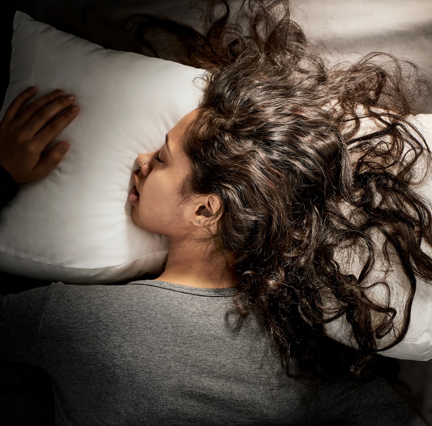 Femme dormant la tête posée sur un oreiller ergonomique SKOGSLÖK avec les cheveux ébouriffés 