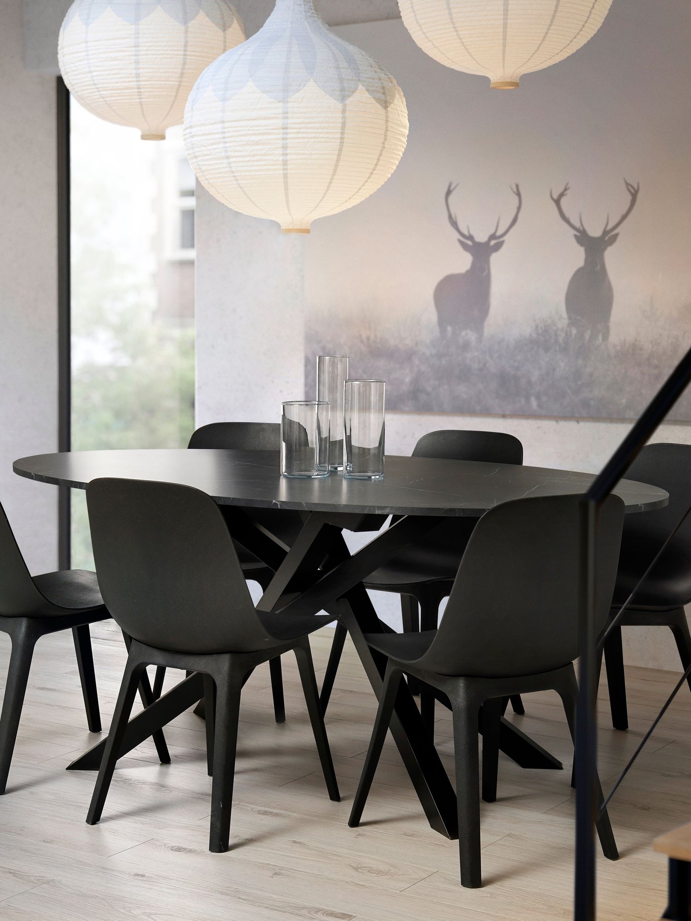 A black oval MARIEDAMM dining table with a marble effect, surrounded by anthracite ODGER bucket chairs in the dining room.