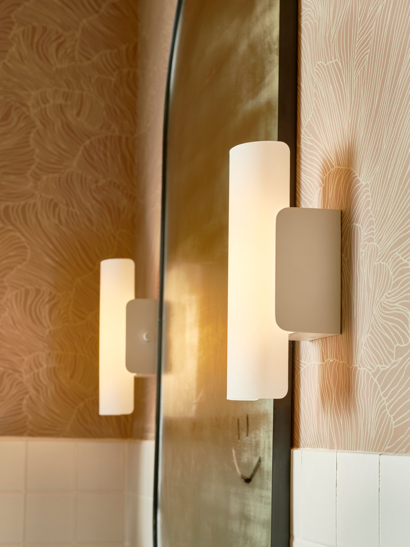 Dos lámparas de pared LED HAVSDUN regulables con vidrio esmerilado colocadas a cada lado de un espejo de baño grande.