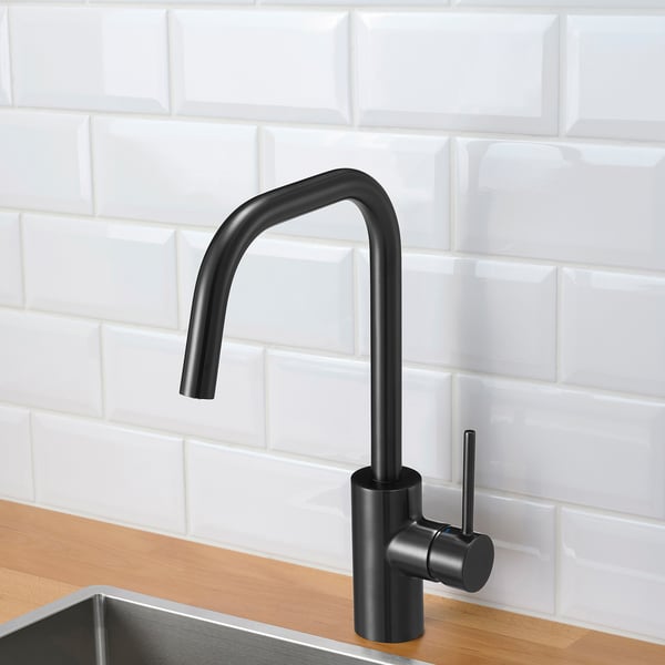 Black kitchen faucet with high arc, on wood counter, white tile backsplash.