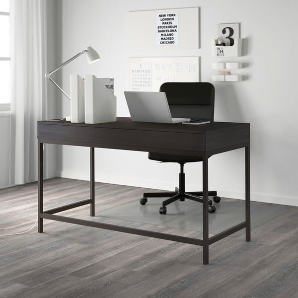 Modern home office with ALEX desk, laptop, drawers, black chair, lamp, minimalist decor.