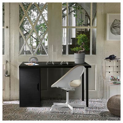 Home office setup with ALEX dark brown desk and white chair, large window, plant, and patterned rug.