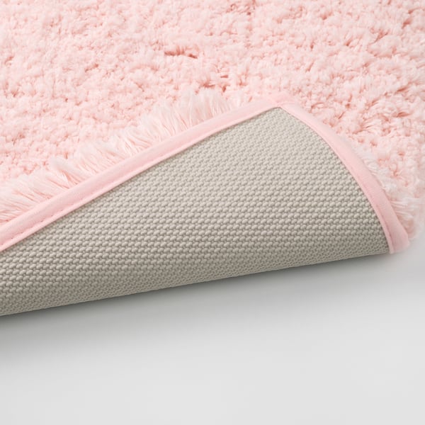Close-up of a soft, pink, plush bath mat with a textured, non-slip base.