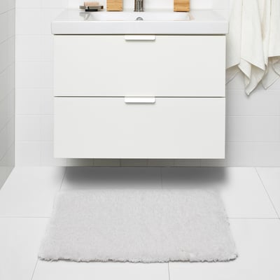 White ALMTJÄRN bath mat, medium, soft polyester, rectangular under vanity.