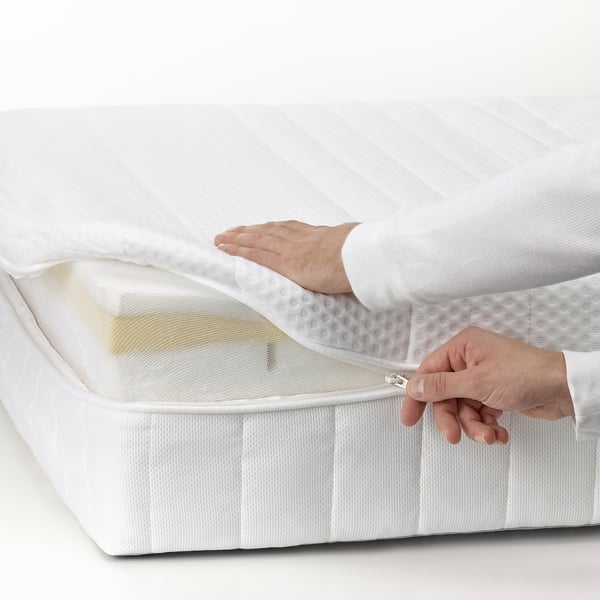 Person lifting mattress cover, displaying memory foam and pocket springs for comfort and support.