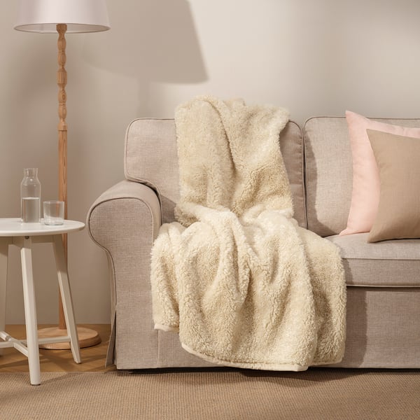 ÅSJORDFLY cream throw on beige sofa, recycled polyester, soft, adds warmth.