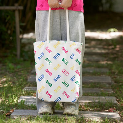 Person holding an IKEA-branded tote bag with colourful logos. The bag appears roomy and designed for various outings.