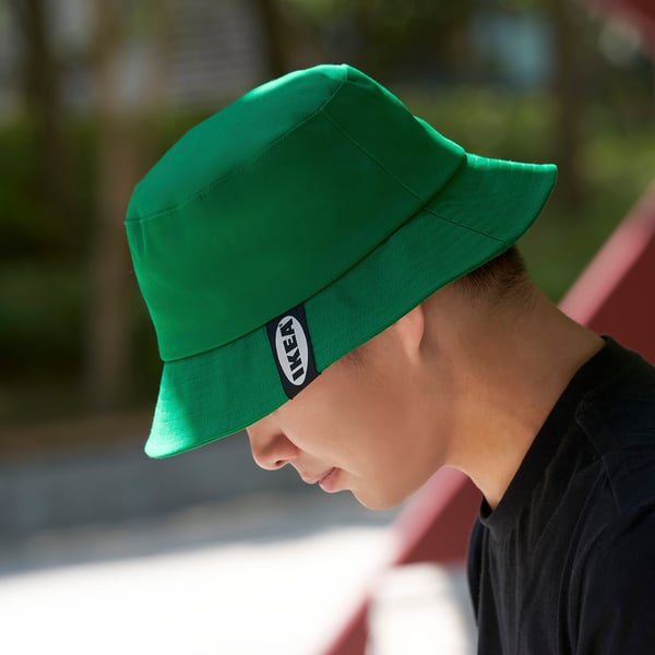 Person wearing a bright green bucket hat with a black logo on the side, likely enjoying outdoor activities.