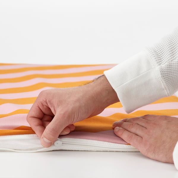 Person holding soft bench pad with zipper, showing removable cover for easy washing.