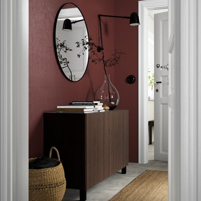 Modern entryway with BESTÅ black & wood sideboard, mirror, vase, basket, white hall.