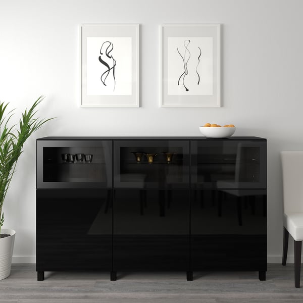 Black glass cabinet with adjustable shelves, displaying cups and bowls, framed art above.