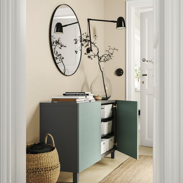 Contemporary hallway with BESTÅ storage unit in blue and black; open doors, wicker basket, mirror, and plant.