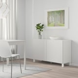 Modern BESTÅ sideboard with shelves, desk, chair, plant, and poster.