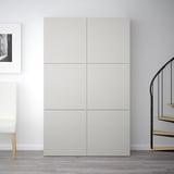 White BESTÅ cabinet with four doors, tall against wall, near spiral staircase and chair.