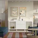 Modern living room with white BESTÅ sideboard, art prints, sofa, coffee table, and colourful rug.