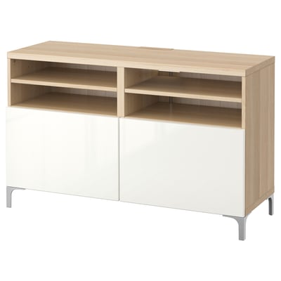 An ikea BESTÅ tv bench in white and light oak. It has open shelves and closed cabinets with a sleek, modern design.
