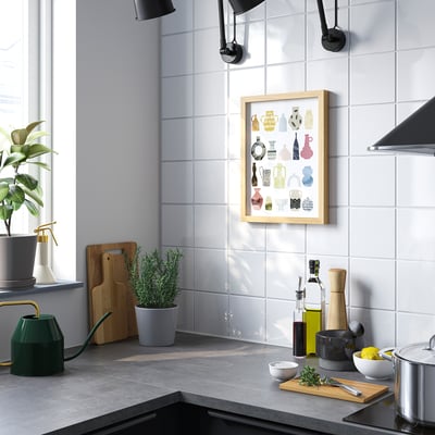 Modern kitchen with large poster of colorful vases behind counter, plants, and kitchen tools.