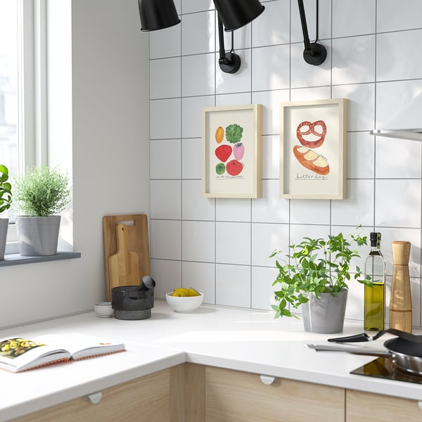 Modern kitchen with vegetable & pretzel posters on tiled walls.