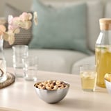 Stainless steel bowl with nuts on table, surrounded by glasses and lemonade.