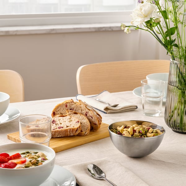 Breakfast table with cereal, bread, nuts, and flowers.