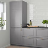 Stylish grey kitchen unit with gold handles, tall and narrow, surrounded by white tiles and plants, offering ample storage.
