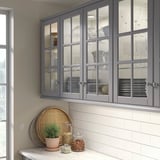 Gray BODBYN glass-door cabinet with cups, glasses, and plant.